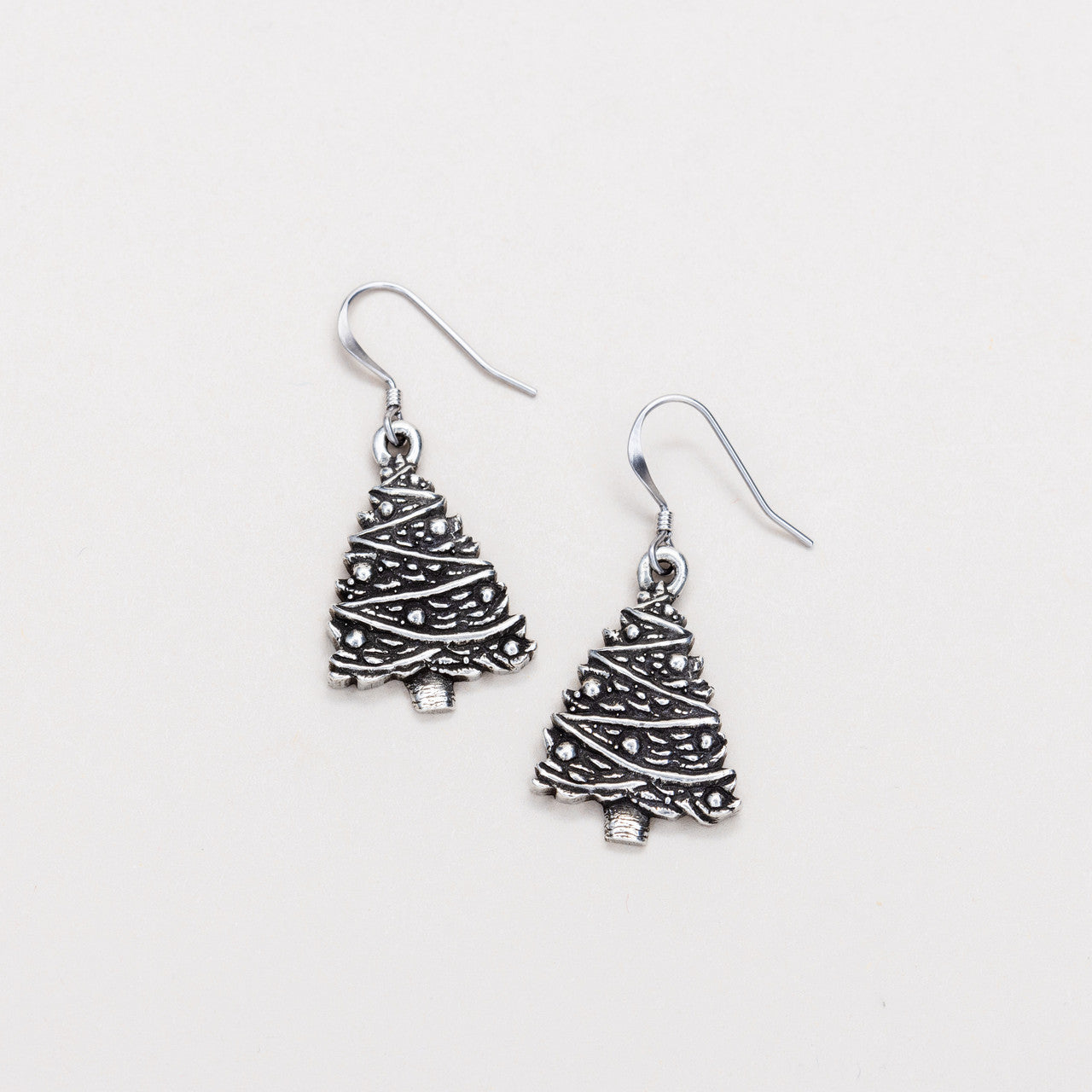 A pair of silver-colored Christmas tree wire earrings on a white background.