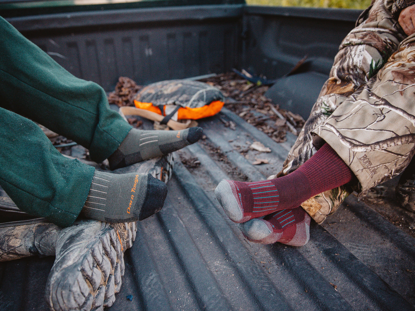 Darn Tough Women's and Men's Hunting socks on models sitting in bed of truck in hunting clothes