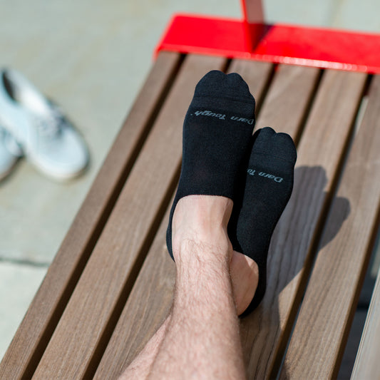 Darn Tough No show black socks on model sitting on bench