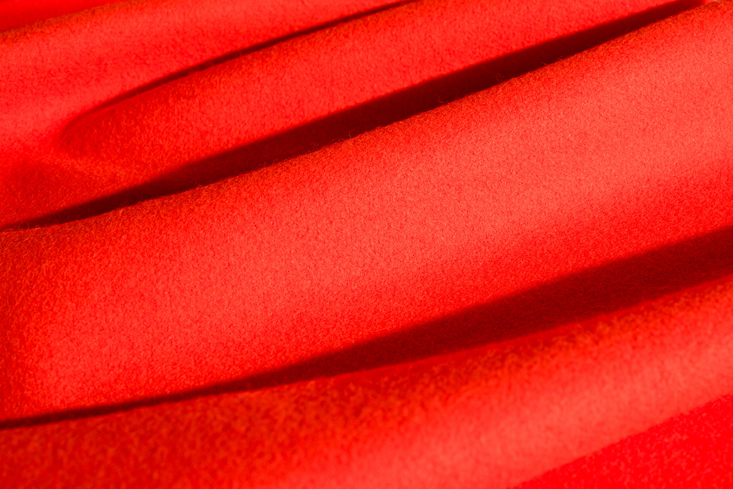 A close-up of a blaze orange wool fabric with a soft, textured weave and draped folds.
