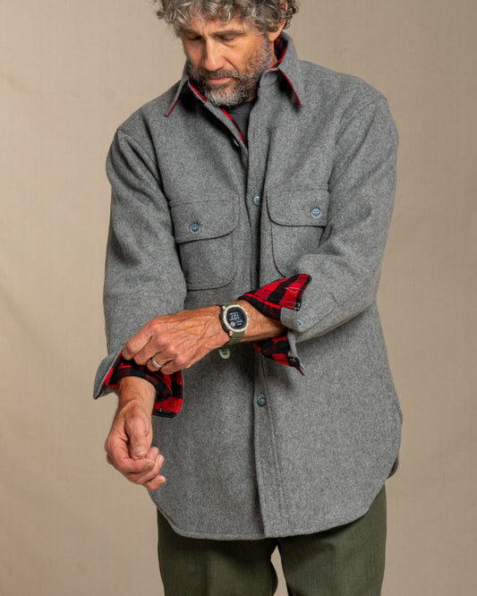 Man wearing a gray wool shirt with red plaid flannel lining, standing against a canvas background