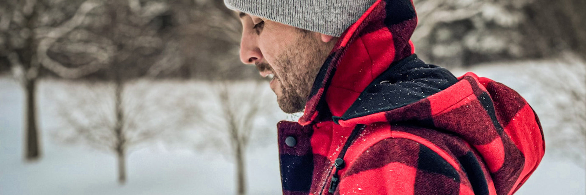 Red black large-check wool jacket with lined hood on model, side view with snow and trees in background