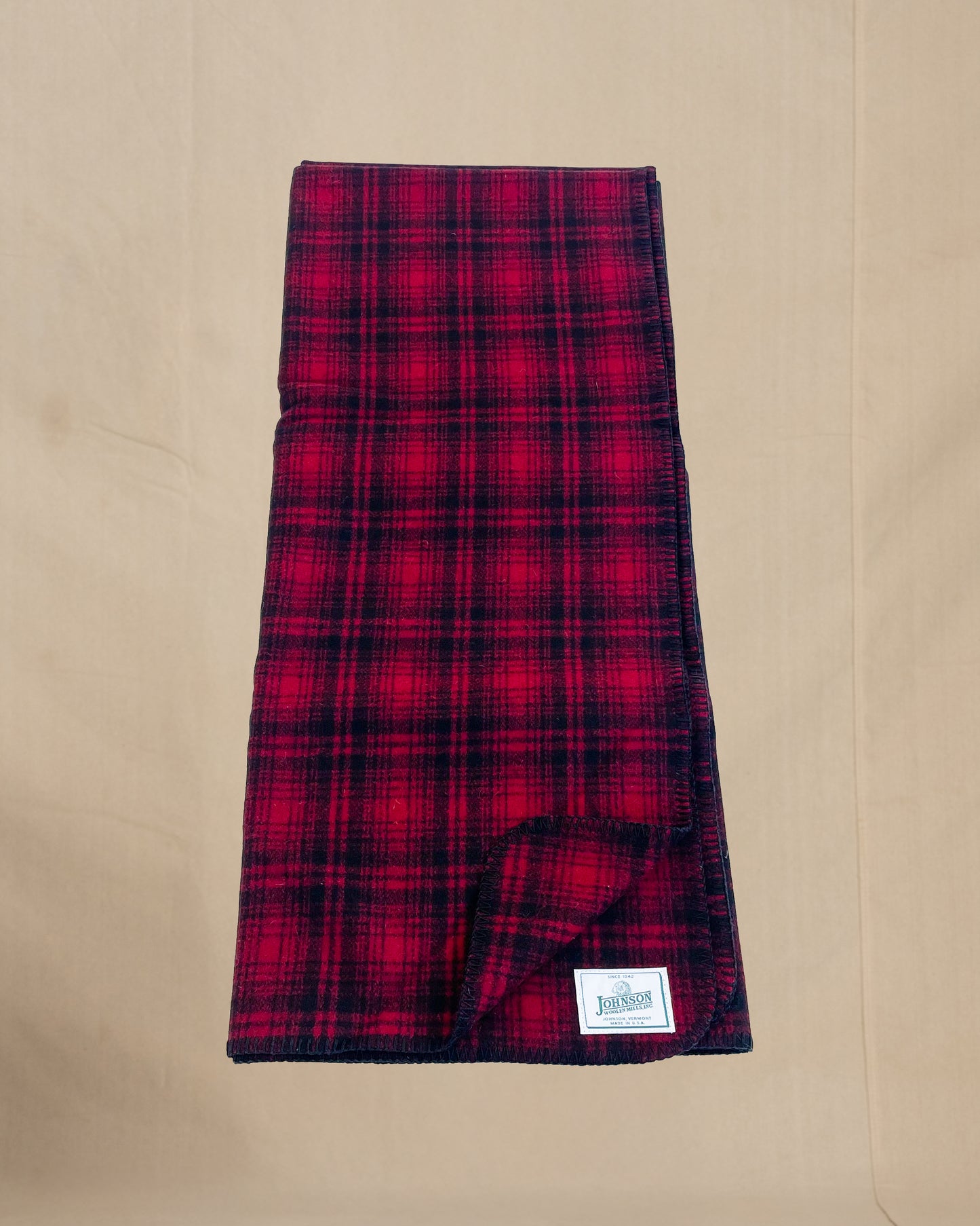Johnson Woolen Mills Red Black Muted Plaid folded blanket length wise showing logo patch