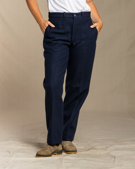 Person wearing navy wool pants on a beige background