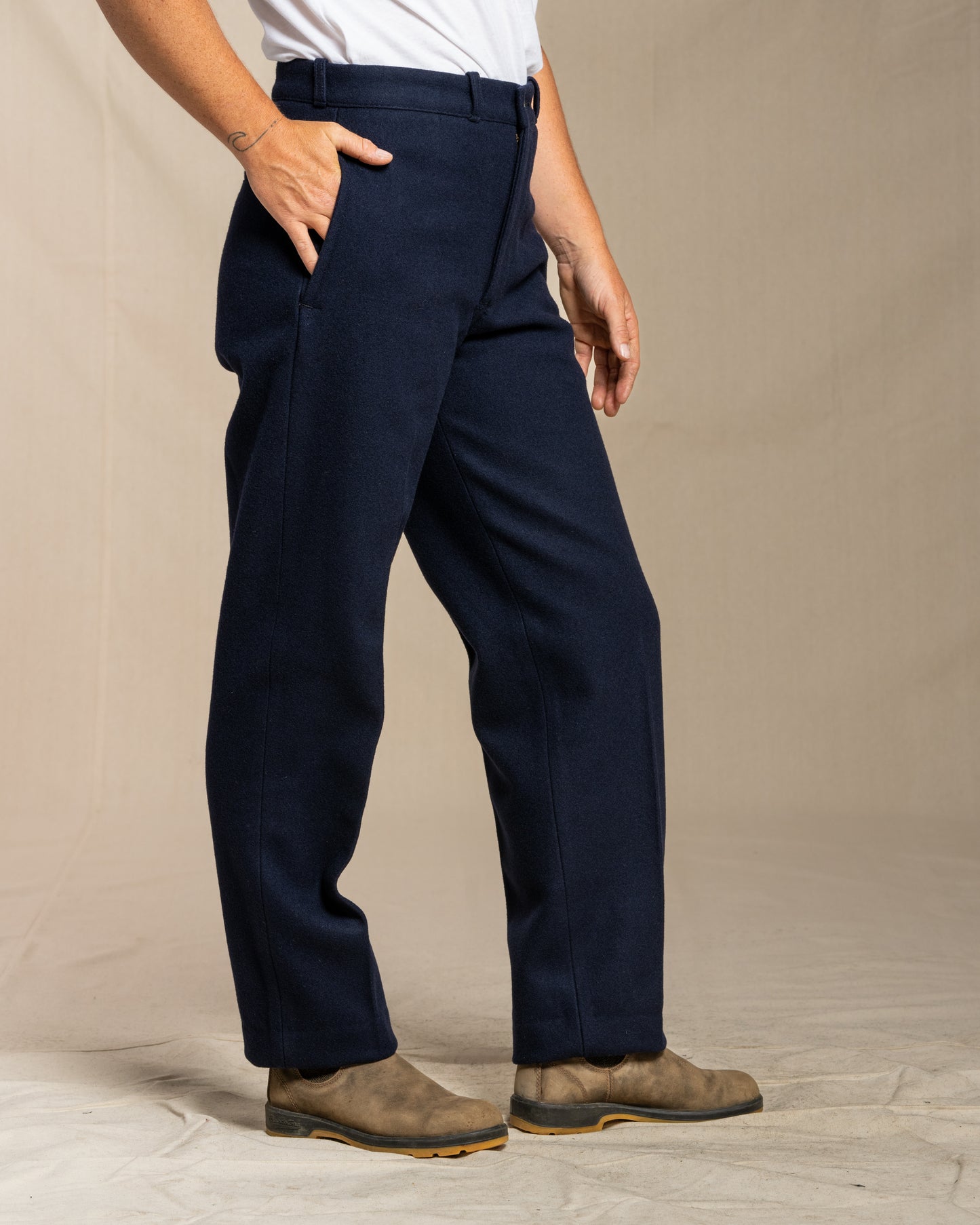Person wearing navy wool pants on a beige background