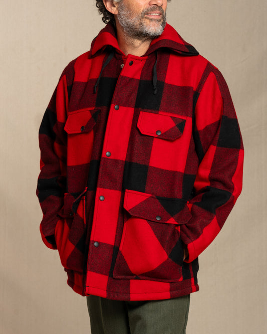 Man wearing a red and black checkered wool jacket against a beige background
