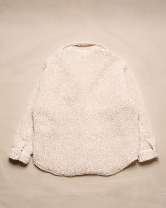 A cream-colored sherpa fleece jacket shown from the back, laid flat on a matching beige textured background.