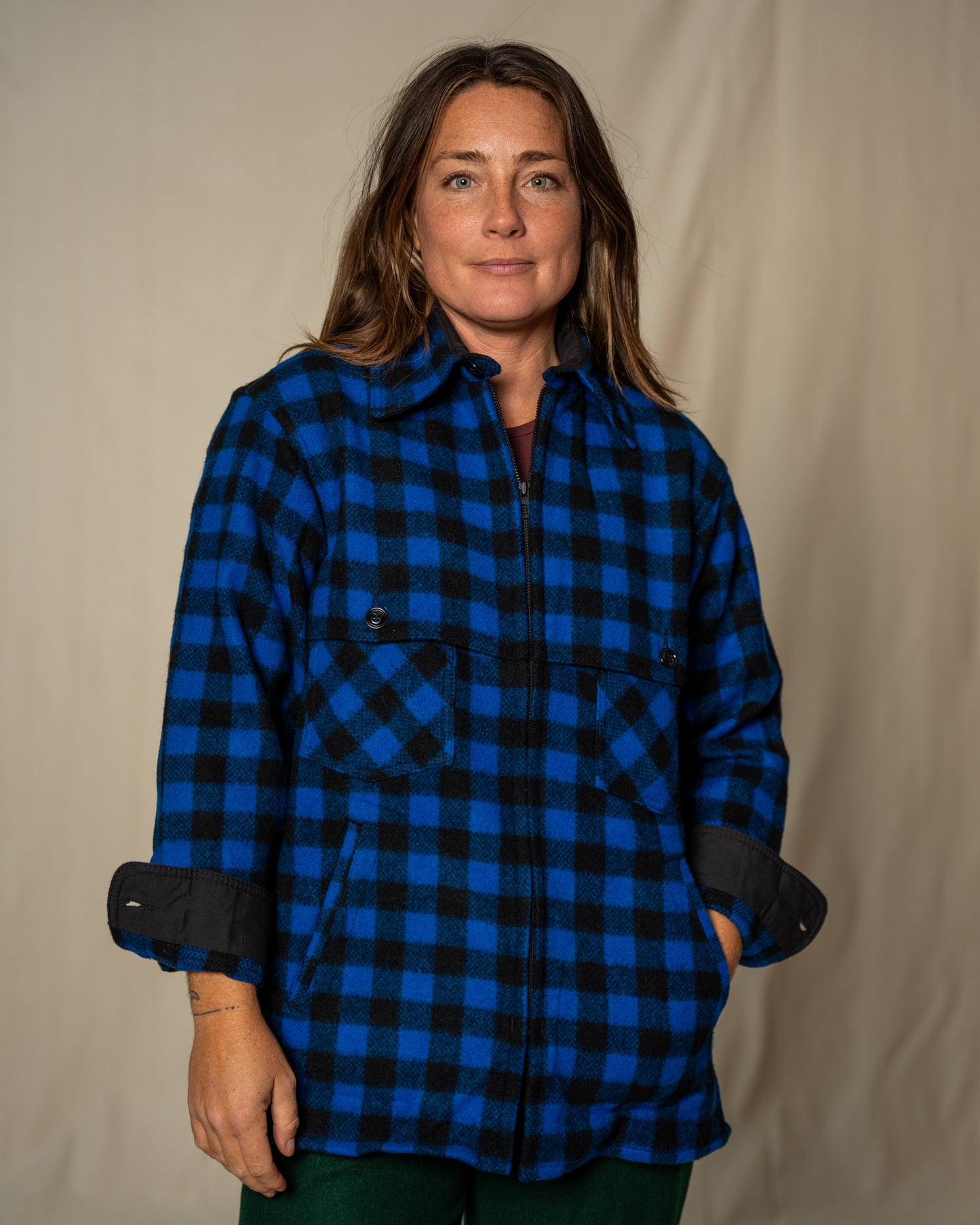 Person wearing a blue and black checkered shirt against a beige background