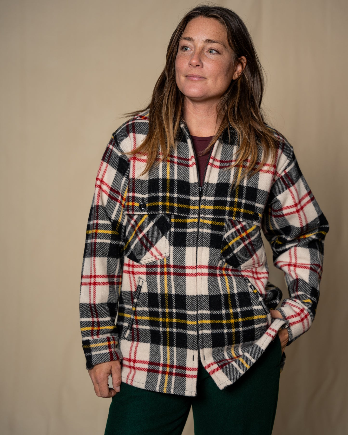 Woman wearing a plaid shirt against a beige background