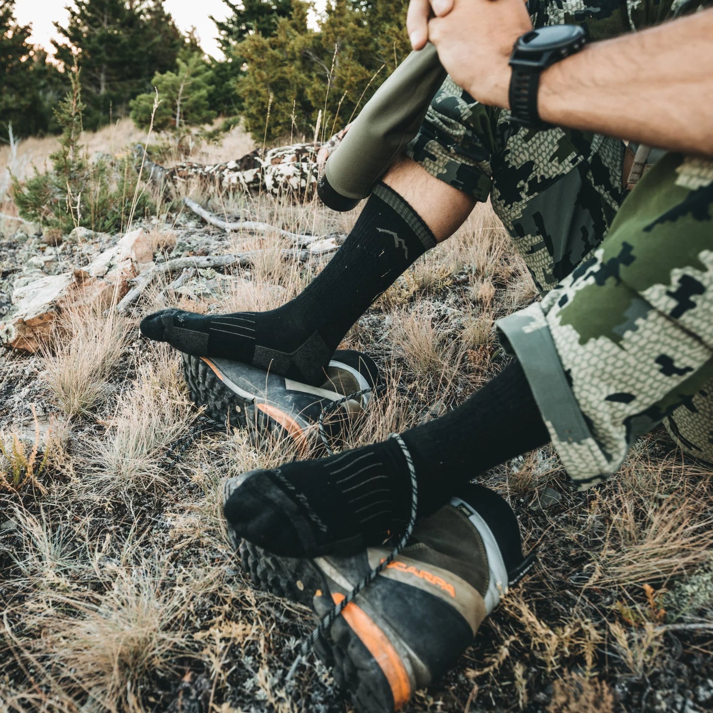 Darn tough socks black shown on person sitting in the grass