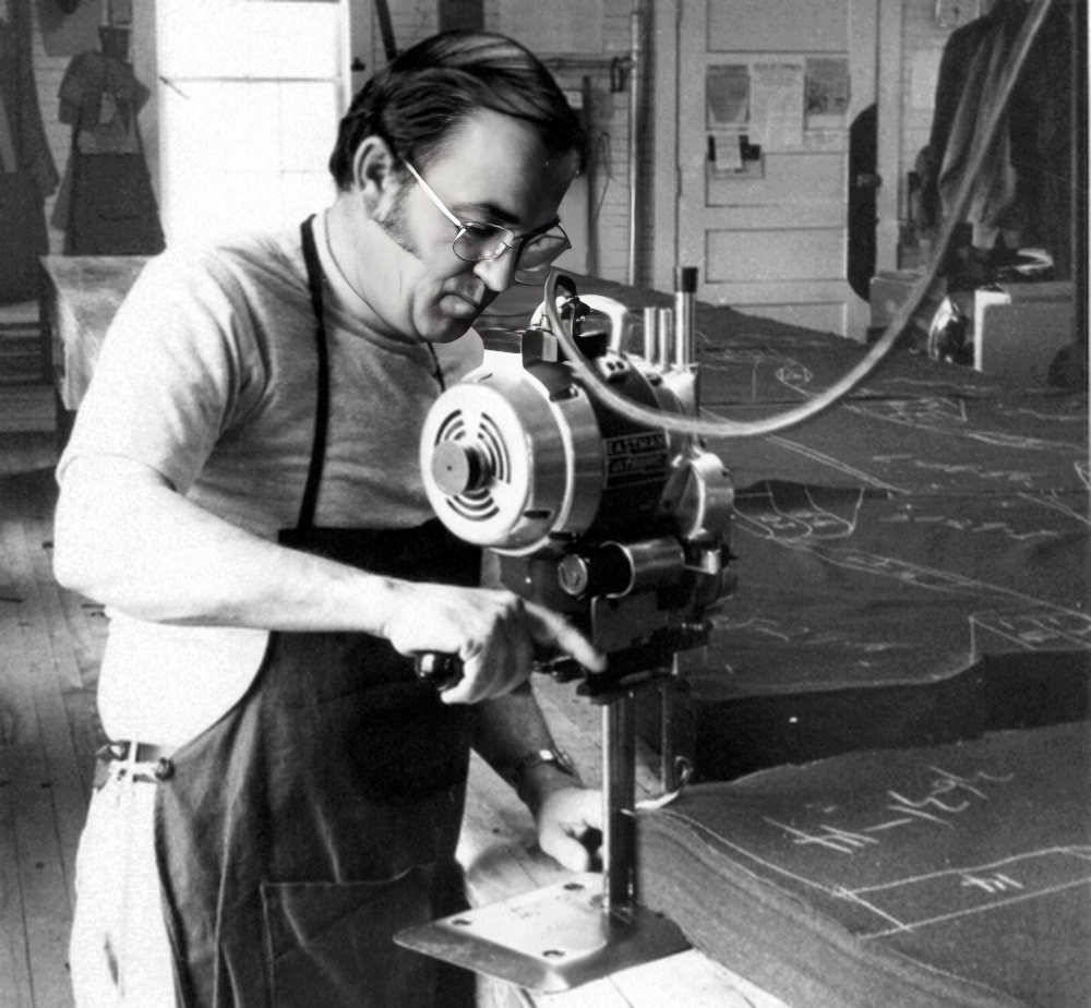 Black and white picture of man cutting stack of wool fabric