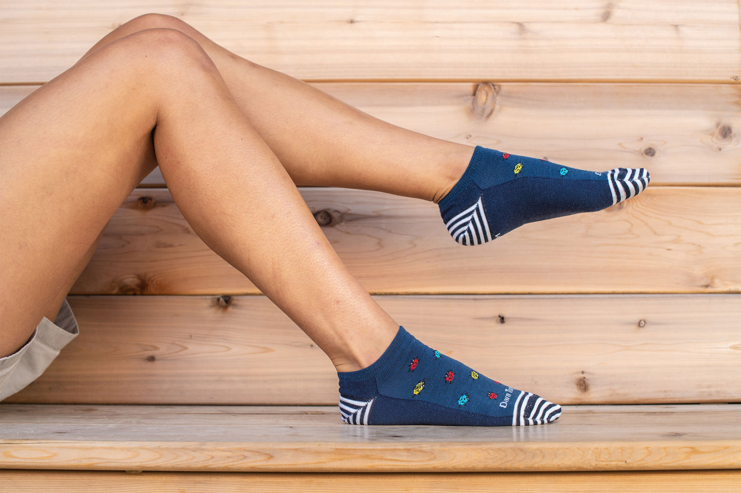 Model laying on wooden bench wearing Darn Tough Lucky Lady No Show Lightweight Lifestyle Sock in Midnight Blue
