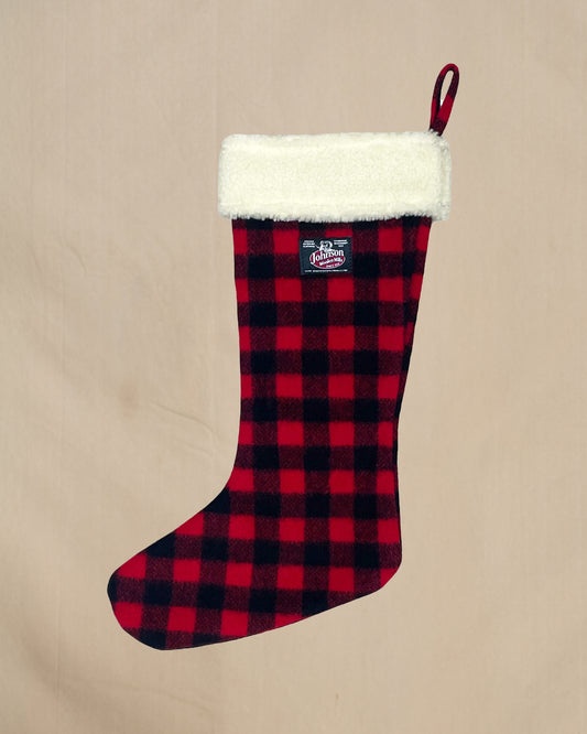 Red and black plaid Christmas stocking with white cuff on a beige background
