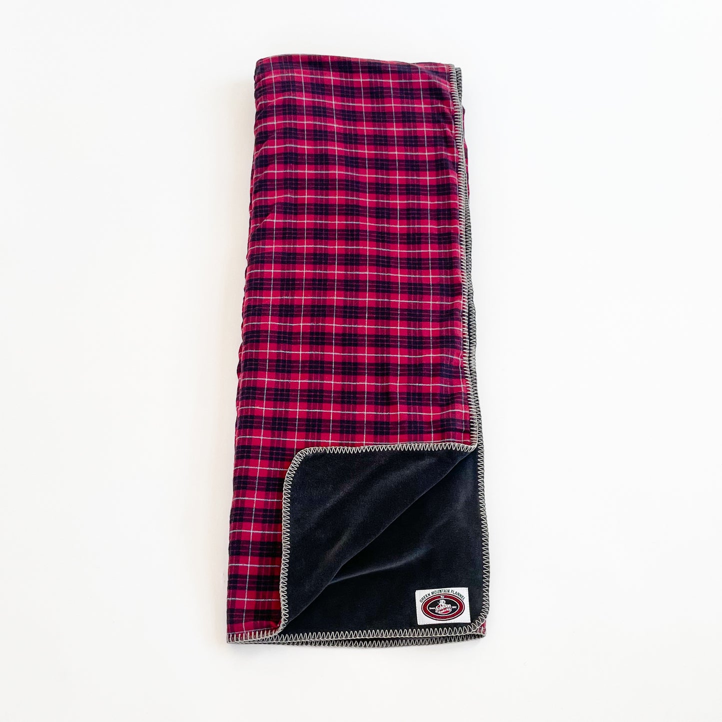 Red, black with white pinstripe plaid Flannel throw blanket laid out with black fleece lining