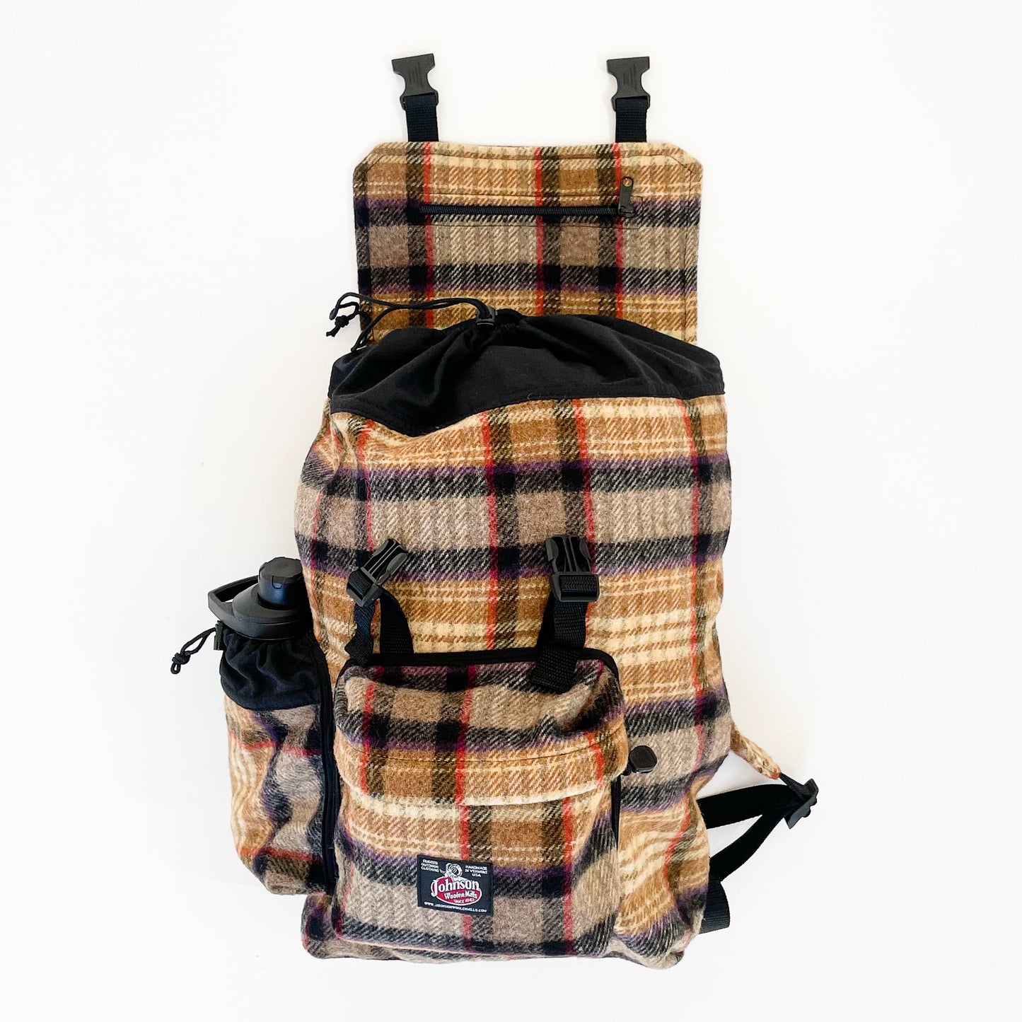 Wool back pack in gold, black and red plaid, shown with water bottle in side pocket and top flap open