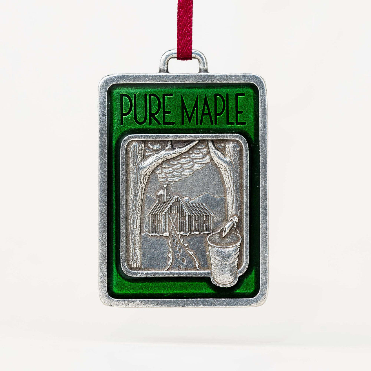 Decorative ornament with 'PURE MAPLE' text and a cabin design on a white background