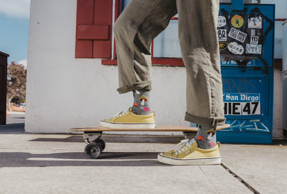 Person wearing yellow sneakers and colorful socks standing on a skateboard with a blue拒车 in the background.