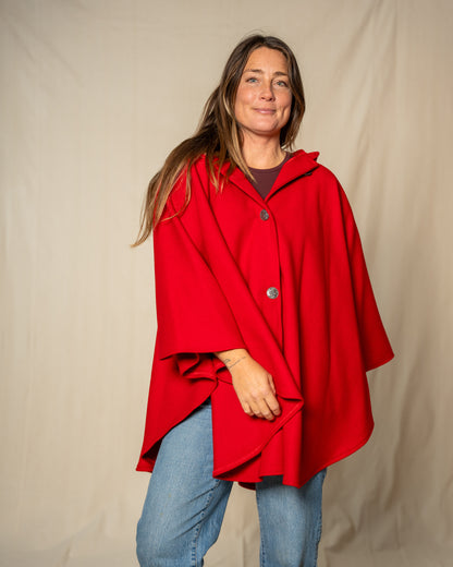 Woman wearing a red cape over a plain background