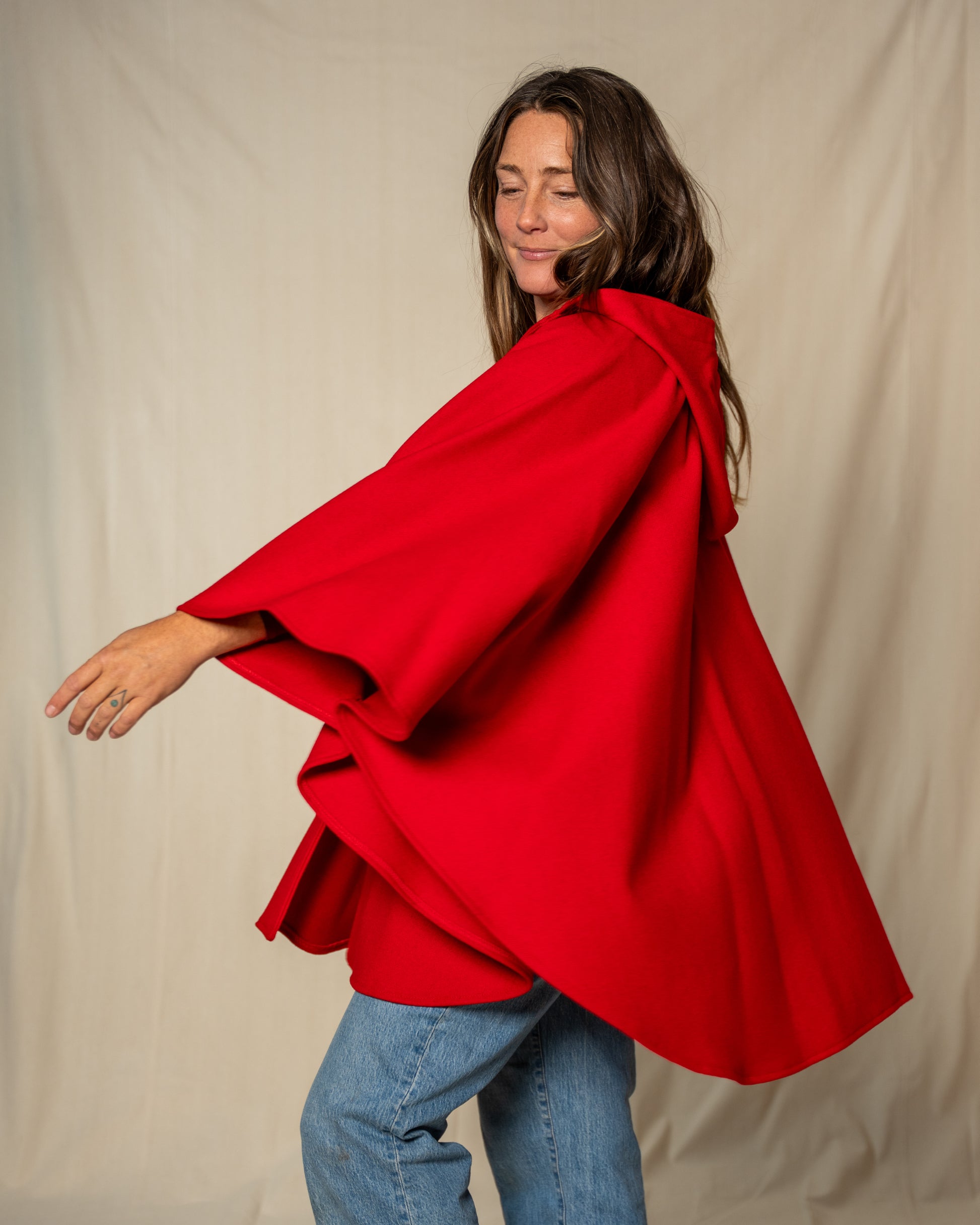 Woman wearing a red cape against a beige background