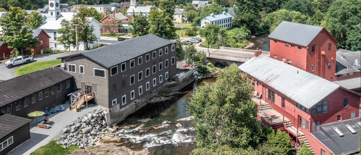 Aerial view of the scenic Johnson VT on the Lamoille River, with a bridge in the background.