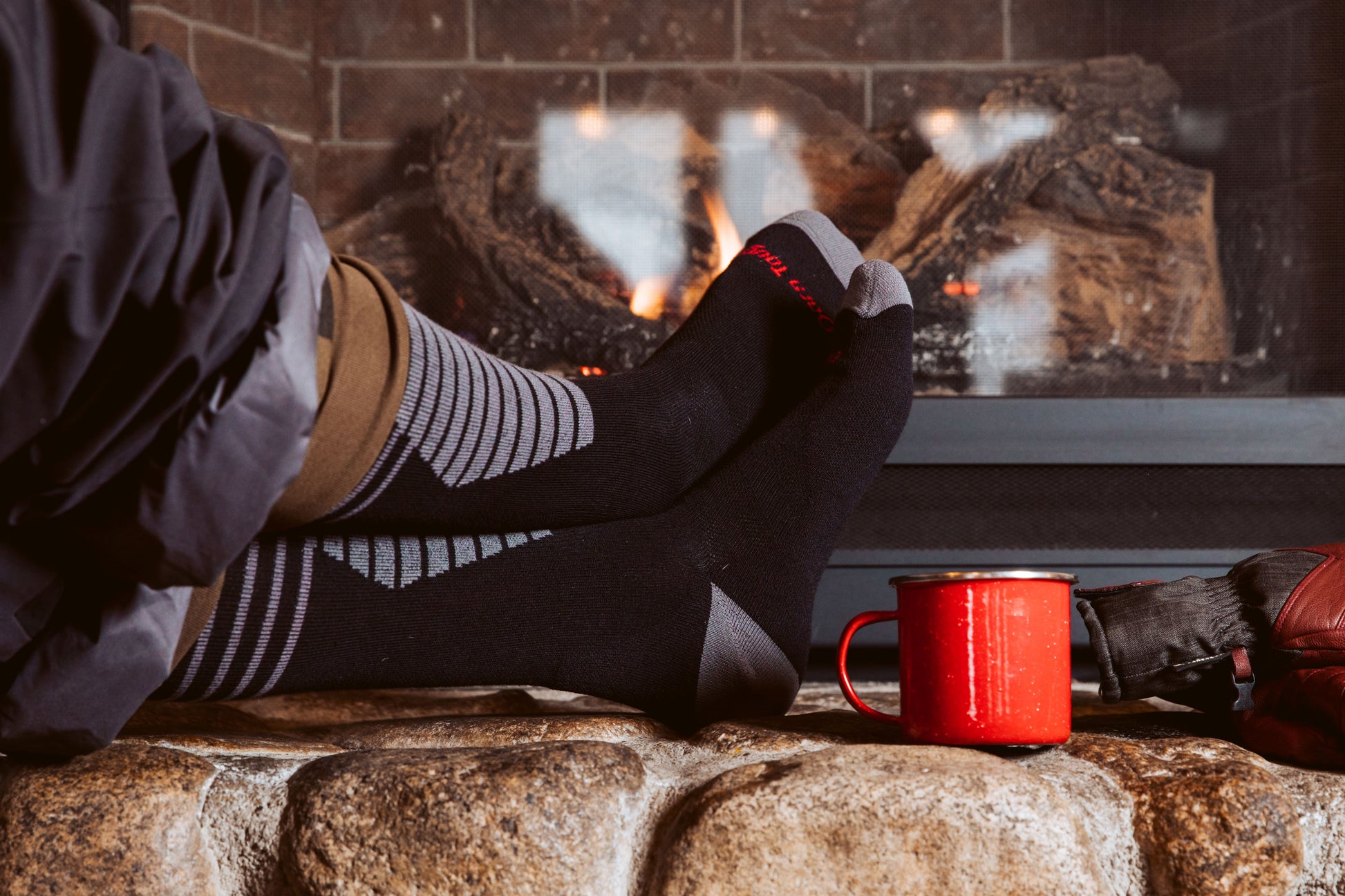 Darn Tough Men's Black Thermolite Edge Over-the-Calf Midweight Ski & Snowboard Sock on model by fireplace