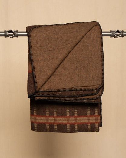 Brown Plaid wool blanket with a leather Johnson label on a beige background