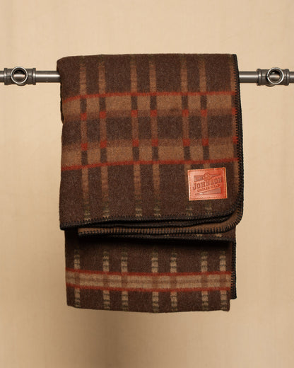 Brown Plaid wool blanket with a leather Johnson label on a beige background