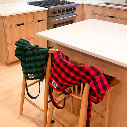 Green and black buffalo check flannel apron and red and black buffalo check flannel apron hanging on chairs in kitchen
