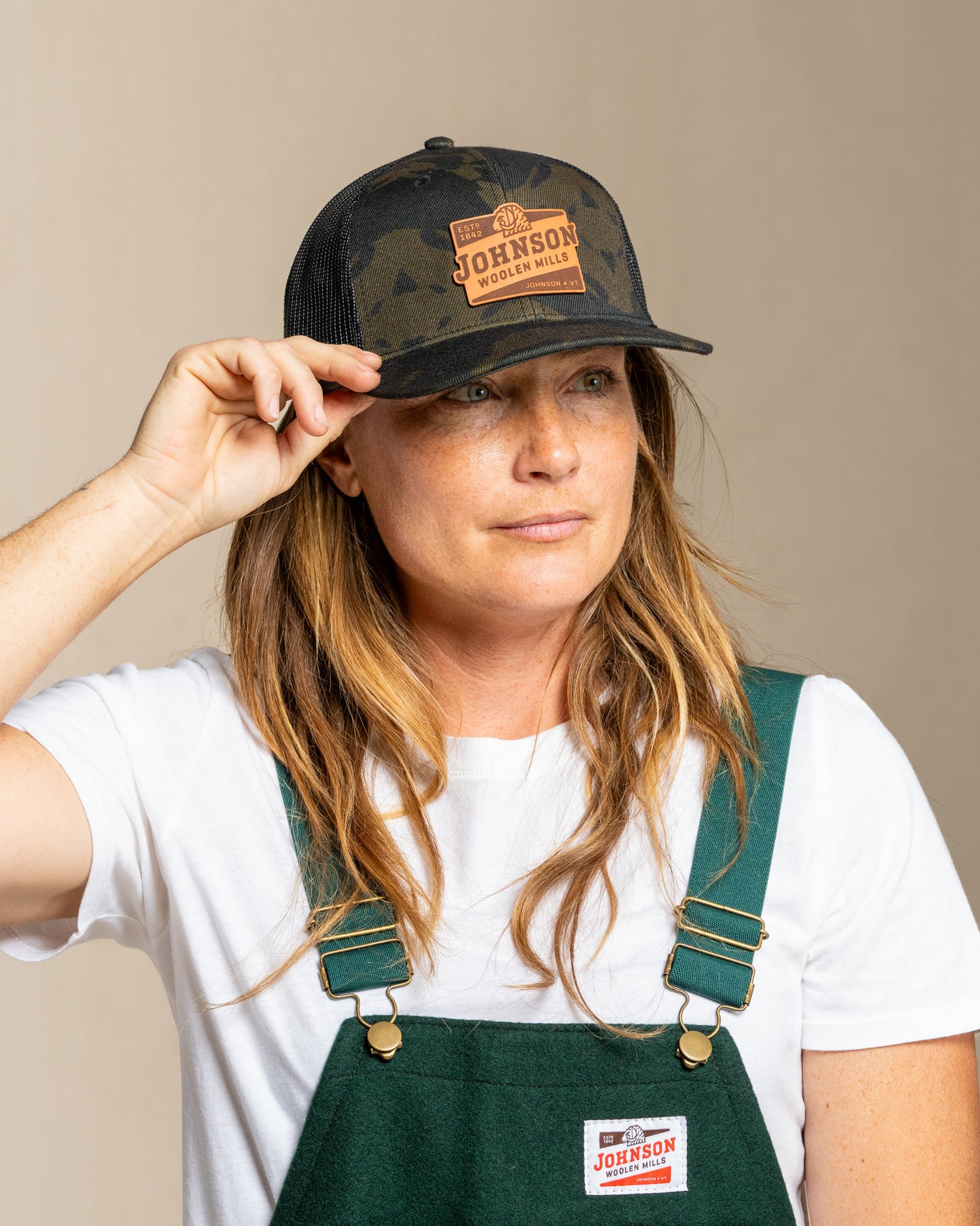 Person wearing a cap and green overalls with a Johnson logo on a beige background