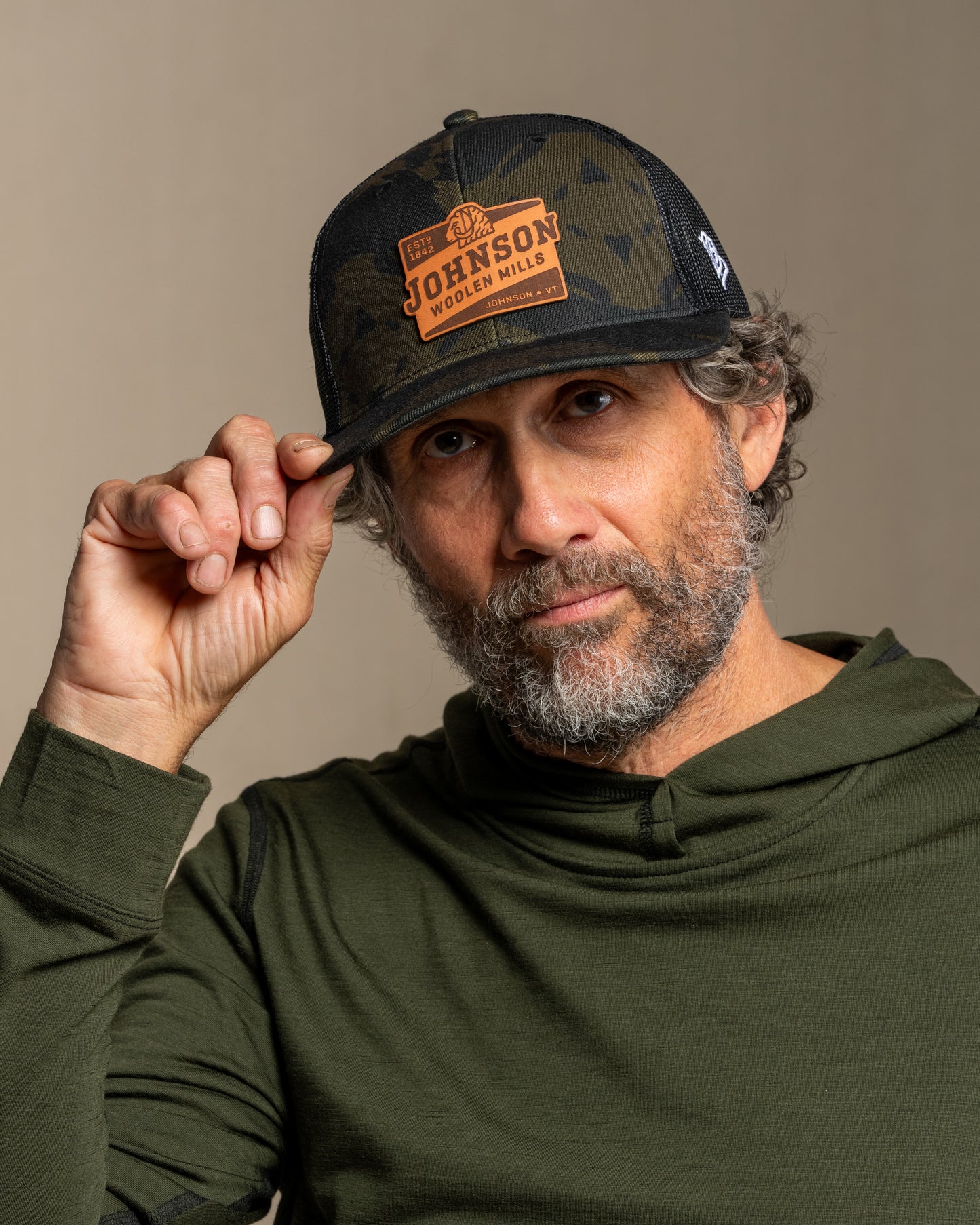 Man wearing a cap with a johnson logo against a neutral background