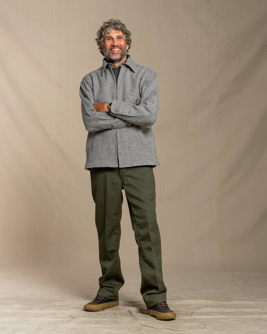 Man wearing a gray twill wool jacket and green pants standing against a plain background