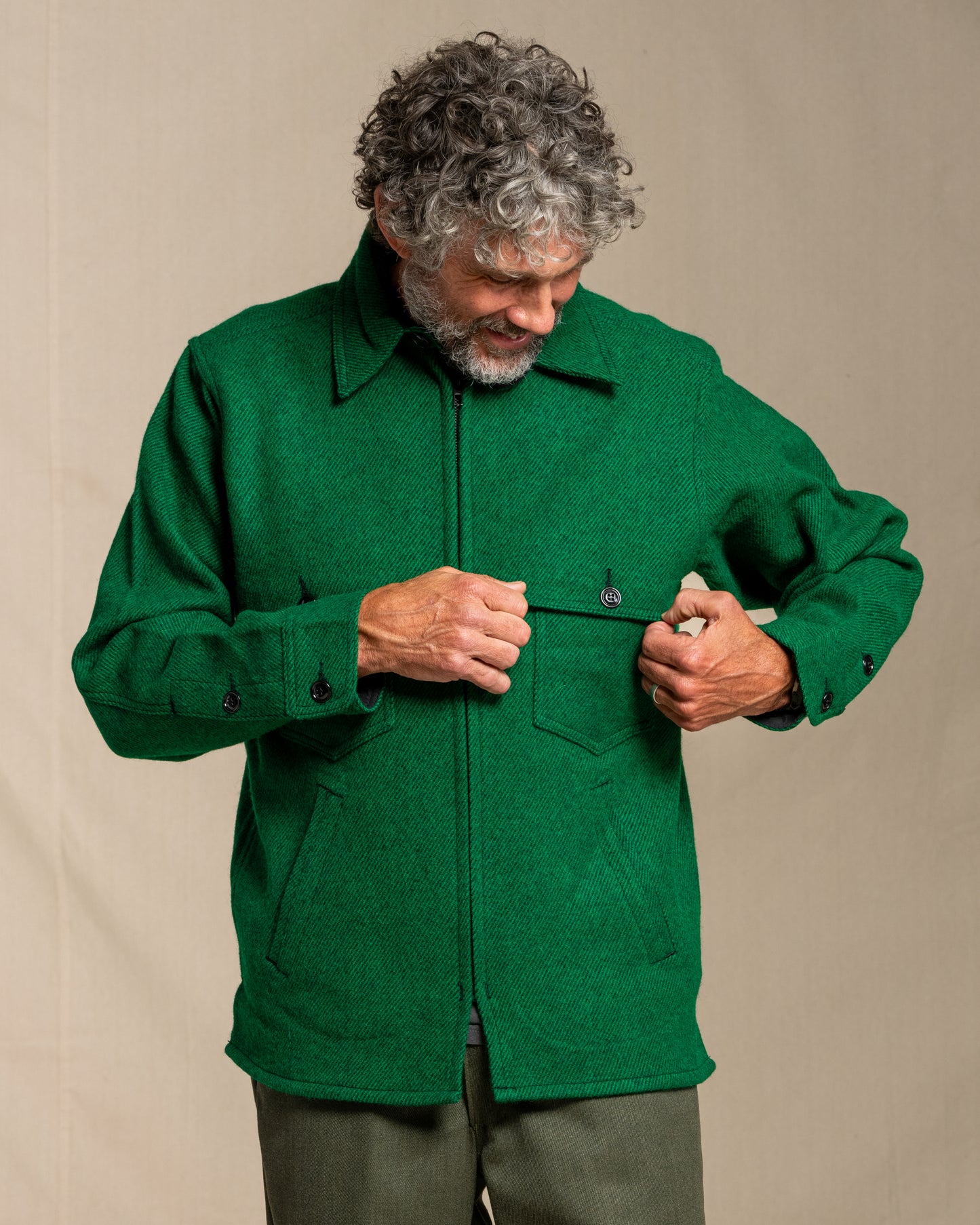 Man wearing a green twill wool jacket against a beige background