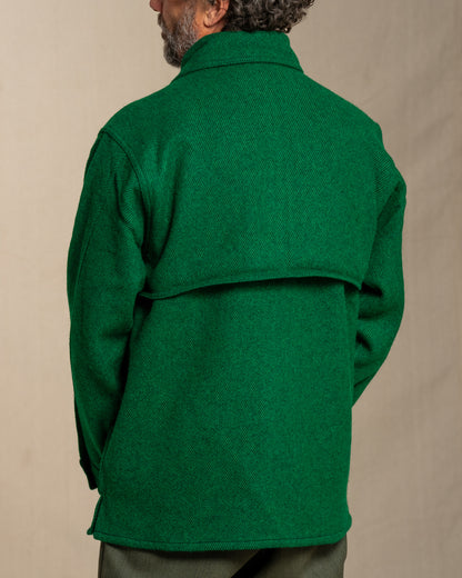 Man wearing a green twill wool jacket against a beige background