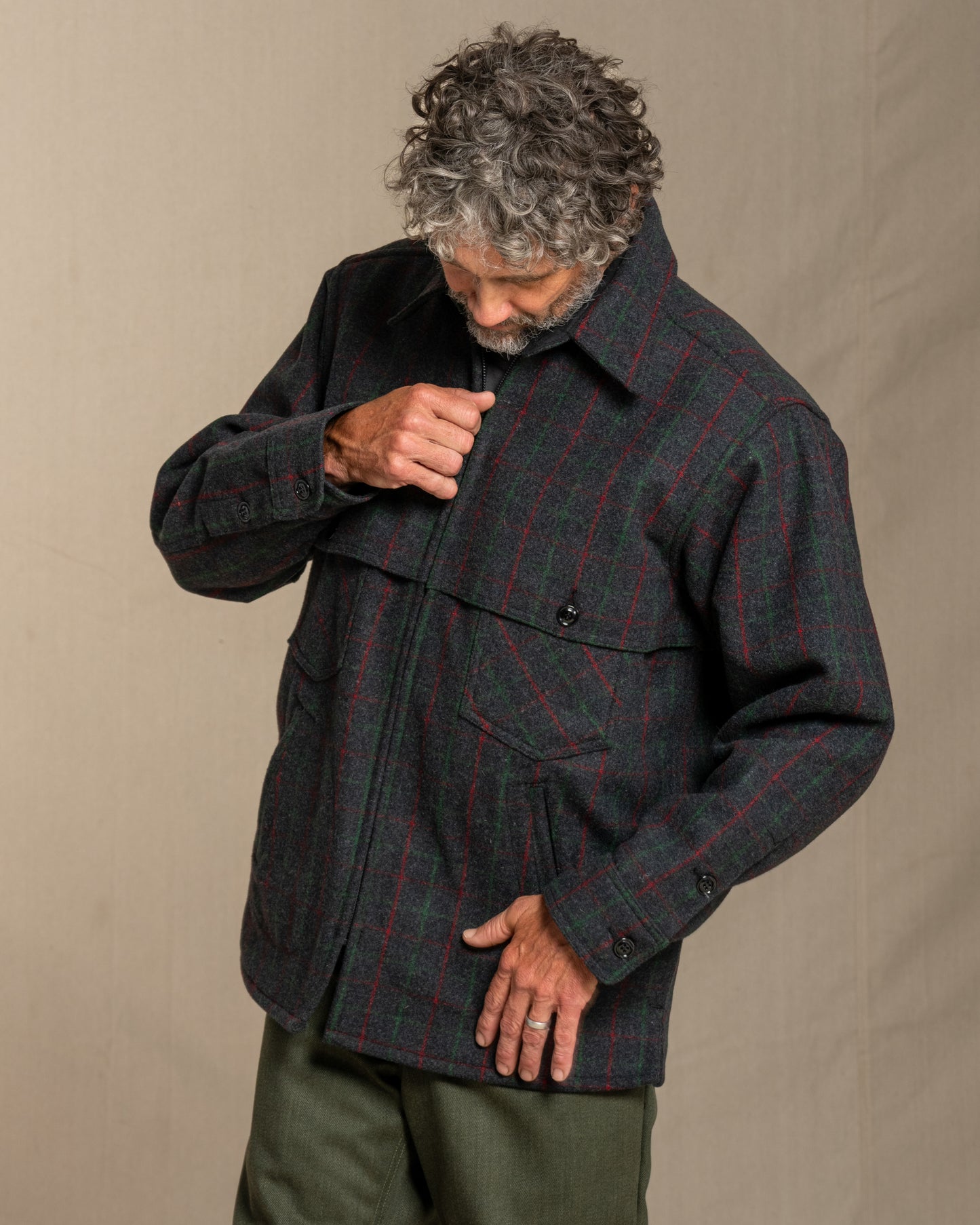 Man wearing a Adirondack plaid wool jacket against a beige background