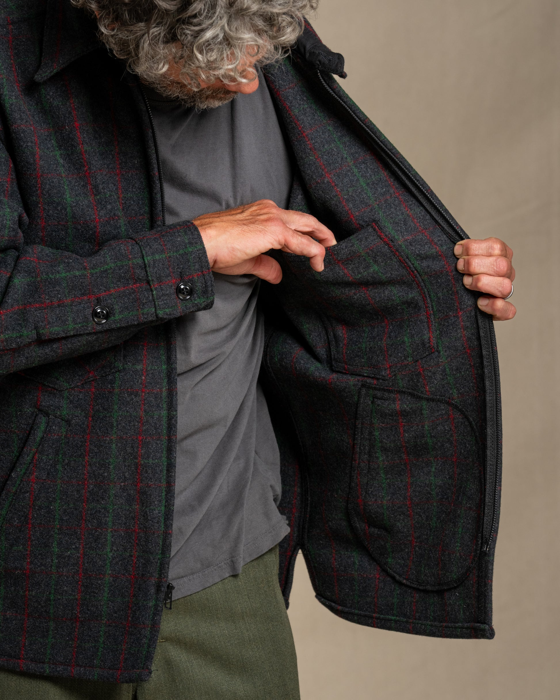 Man wearing a Adirondack plaid wool jacket against a beige background