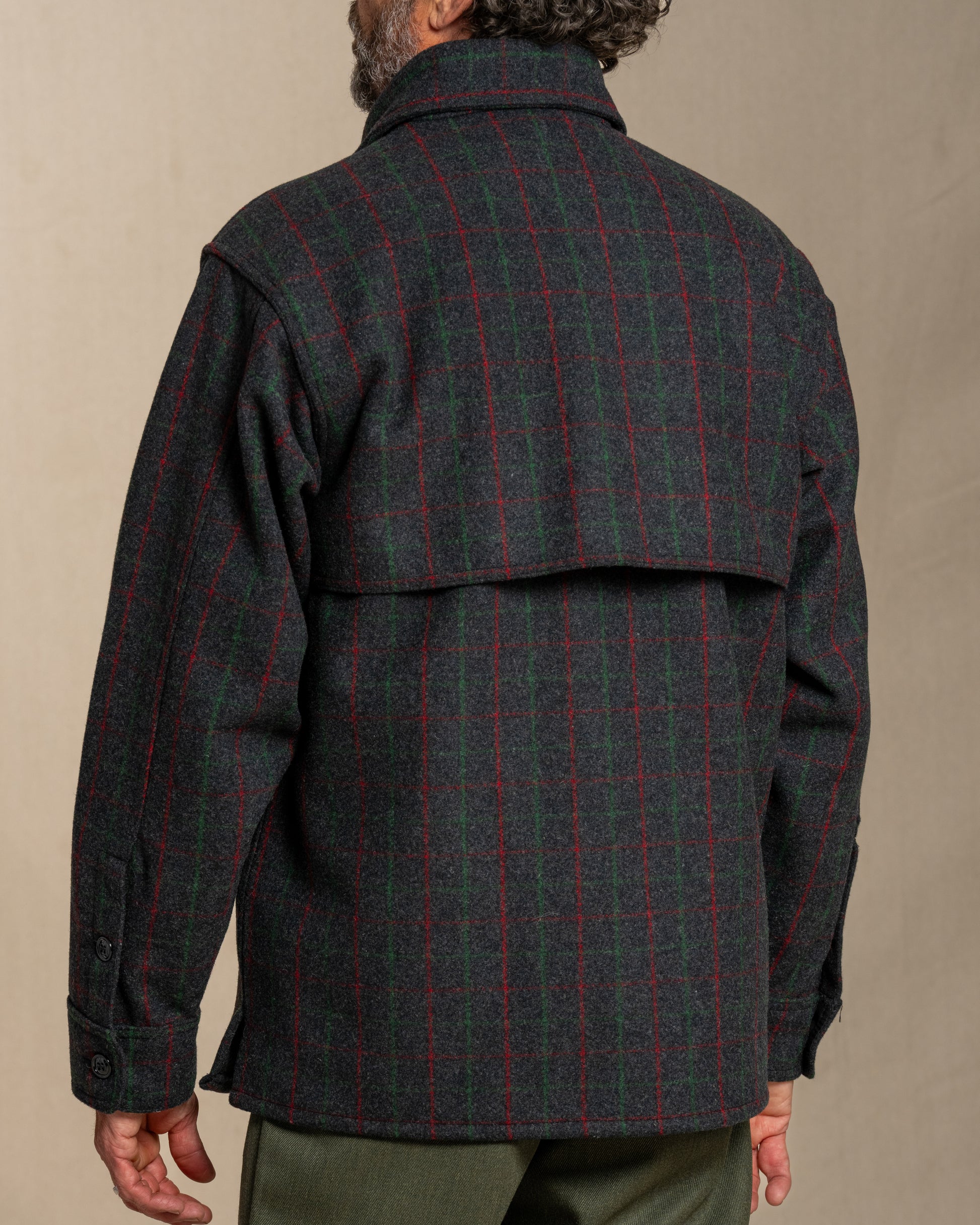 Man wearing a Adirondack plaid wool jacket against a beige background