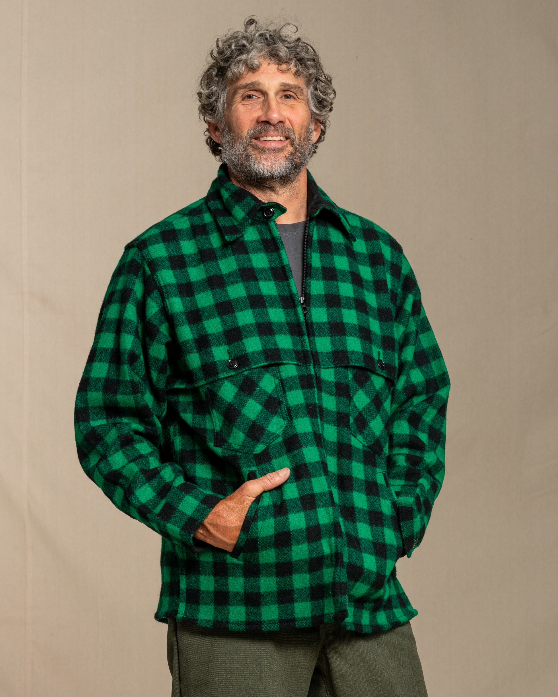 Man wearing a green and black checkered wool shirt against a beige background