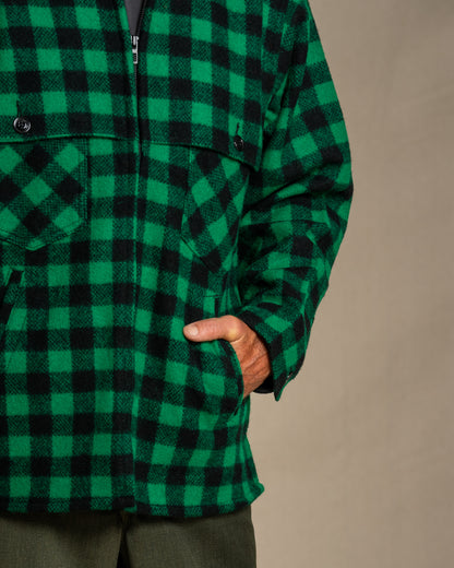 Green and black checkered coat worn by a person on a beige background