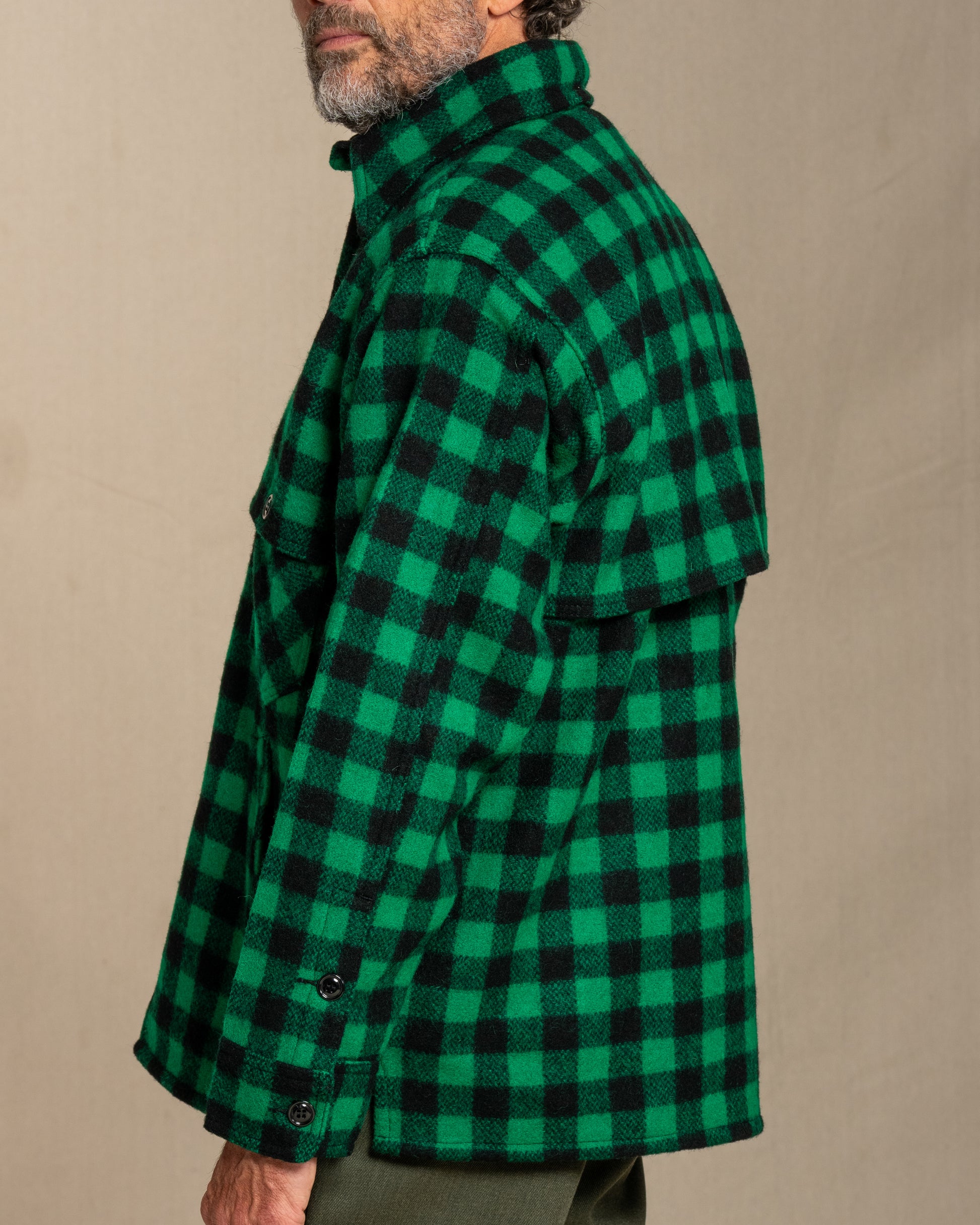 Person wearing a green and black checkered shirt against a beige background