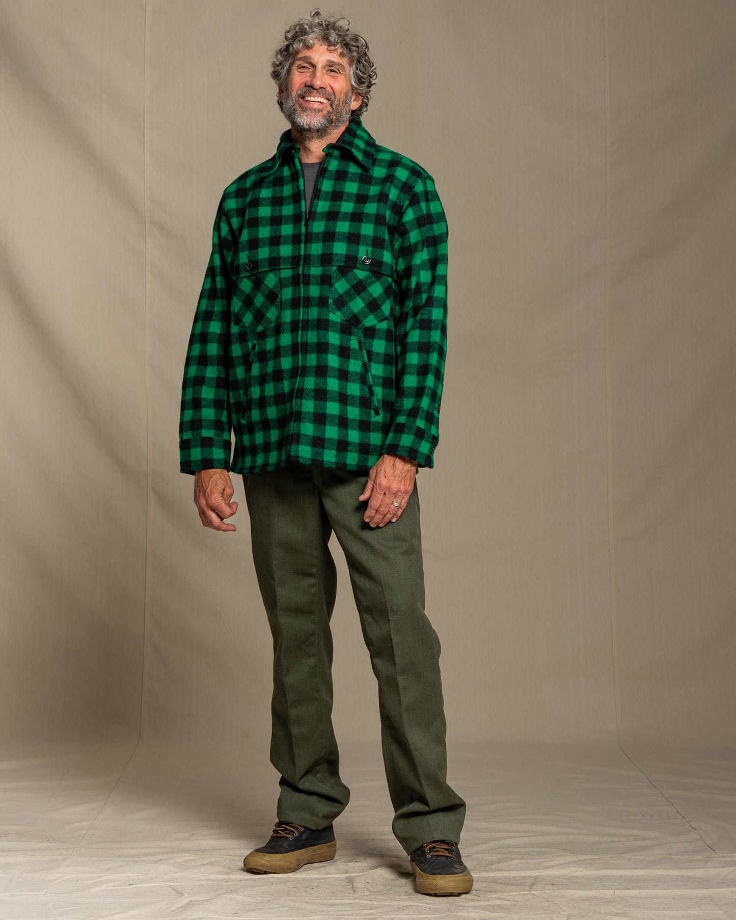 Man wearing a green and black checkered wool shirt against a beige background