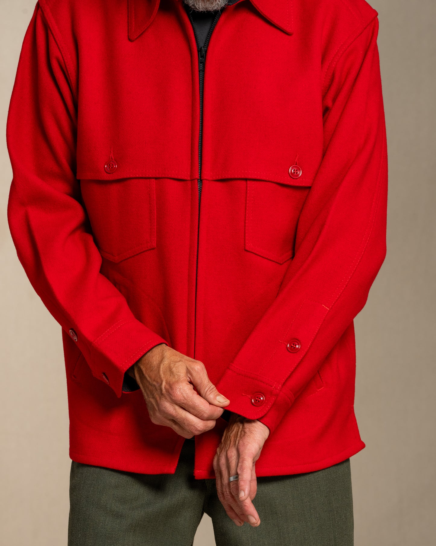 Man wearing a red wool jacket against a beige background