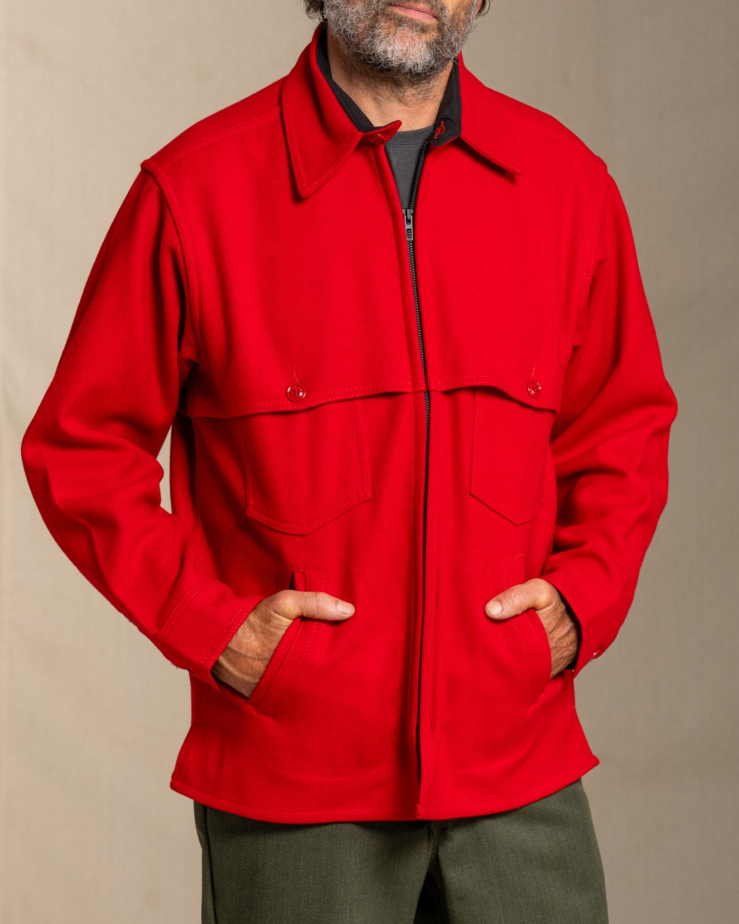 Man wearing a red wool jacket against a beige background