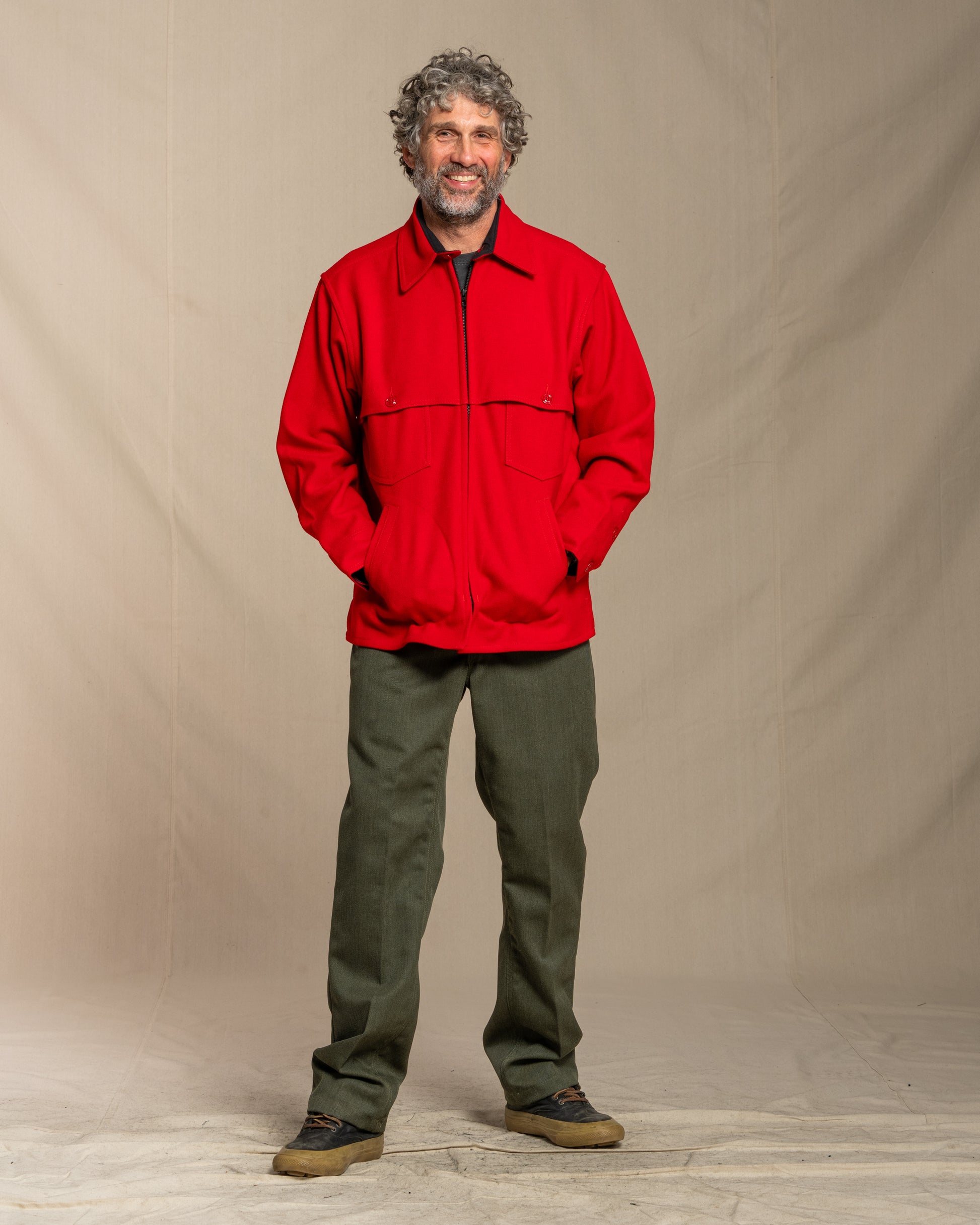 Man wearing a red wool jacket against a beige background