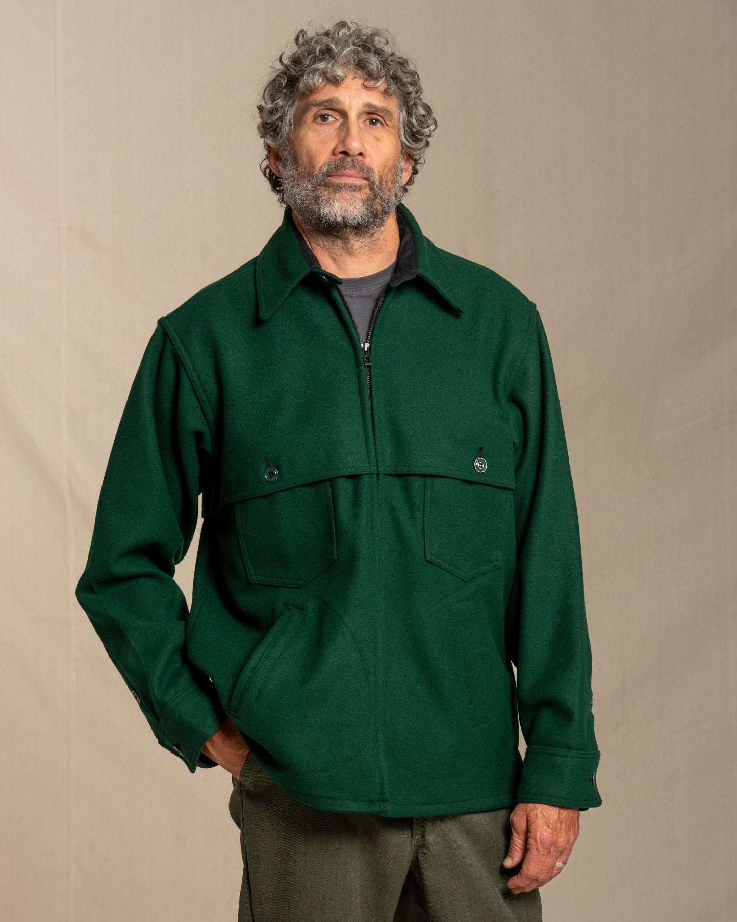 Man wearing a spruce green wool jacket against a beige background