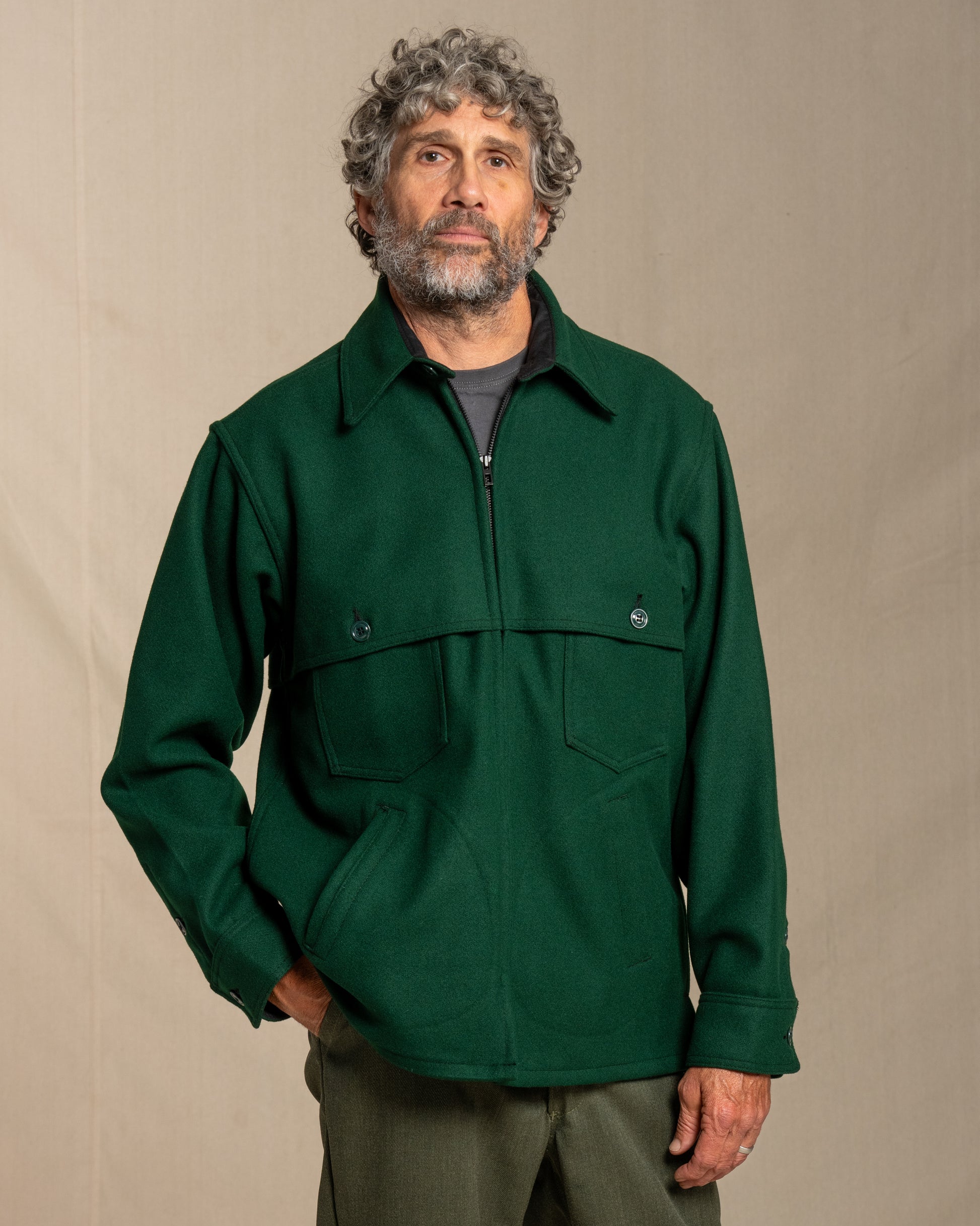 Man wearing a spruce green wool jacket against a beige background