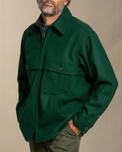 Man wearing a spruce green wool jacket against a beige background