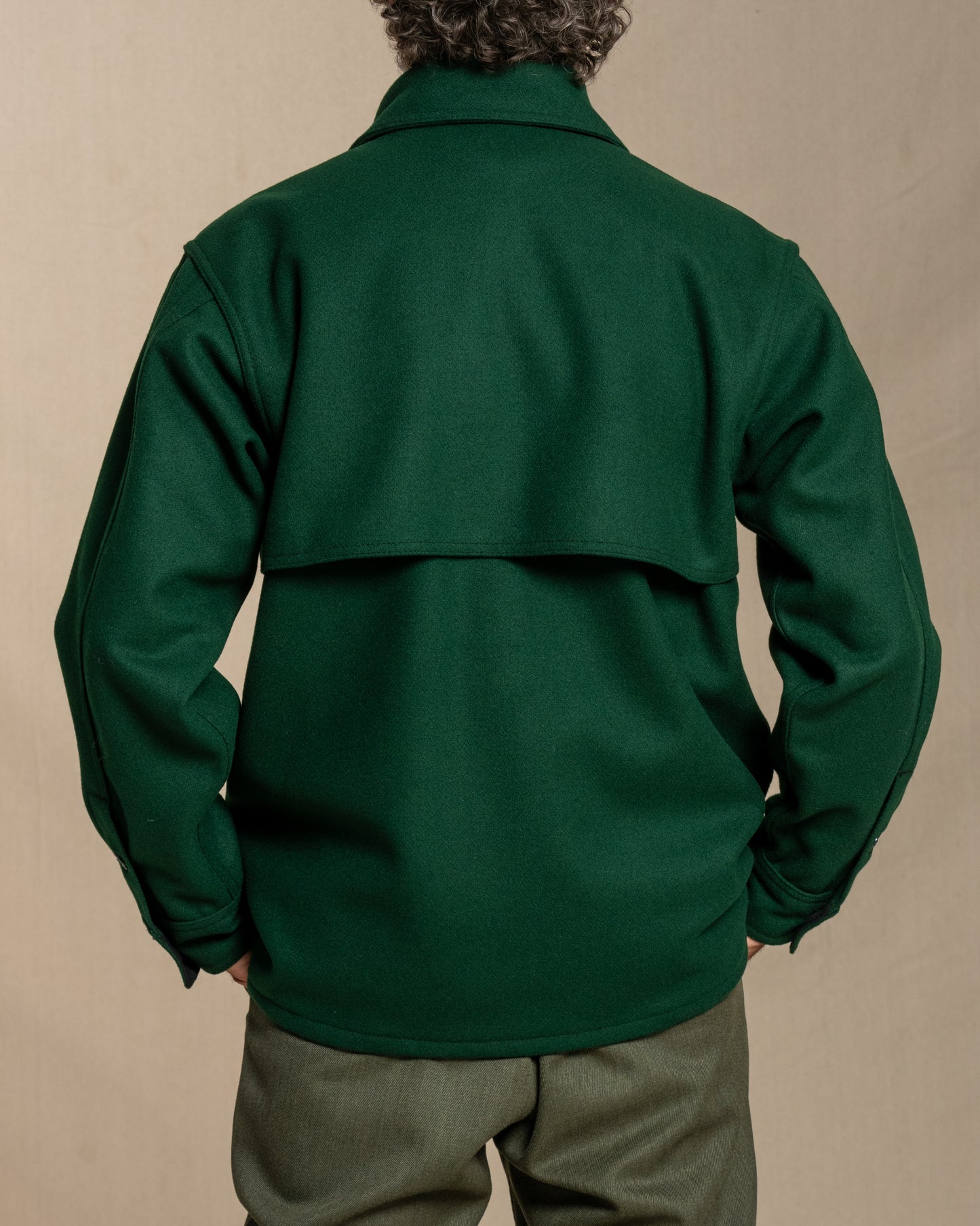 Man wearing a spruce green wool jacket against a beige background