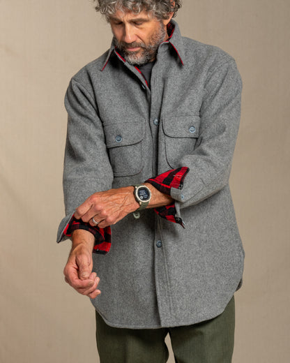 Man wearing a gray wool shirt with red plaid flannel lining, standing against a canvas background