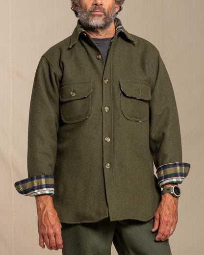 Man wearing a loden wool shirt with plaid cuffs against a beige background