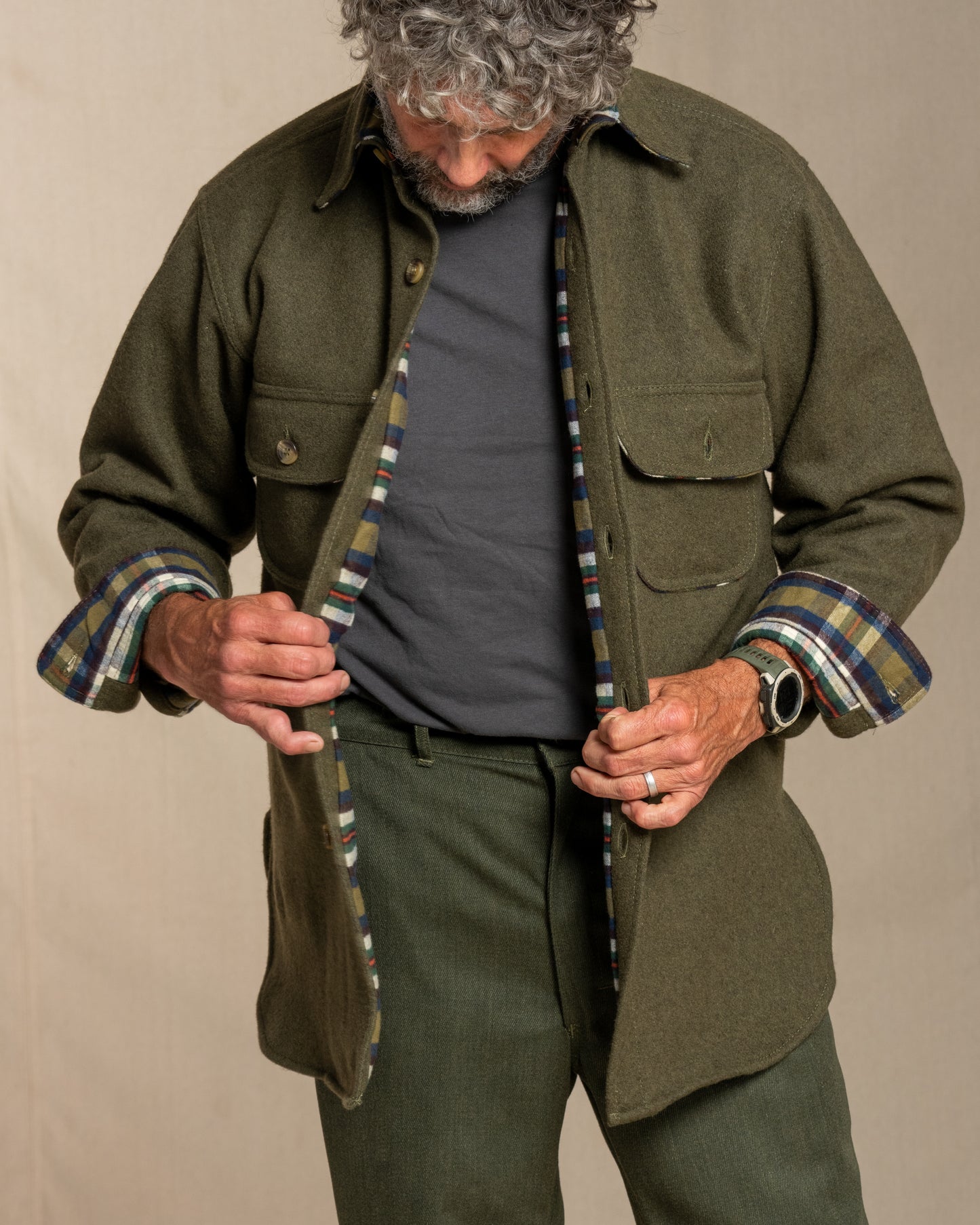 Man wearing a loden wool shirt with plaid flannel lining against a beige background
